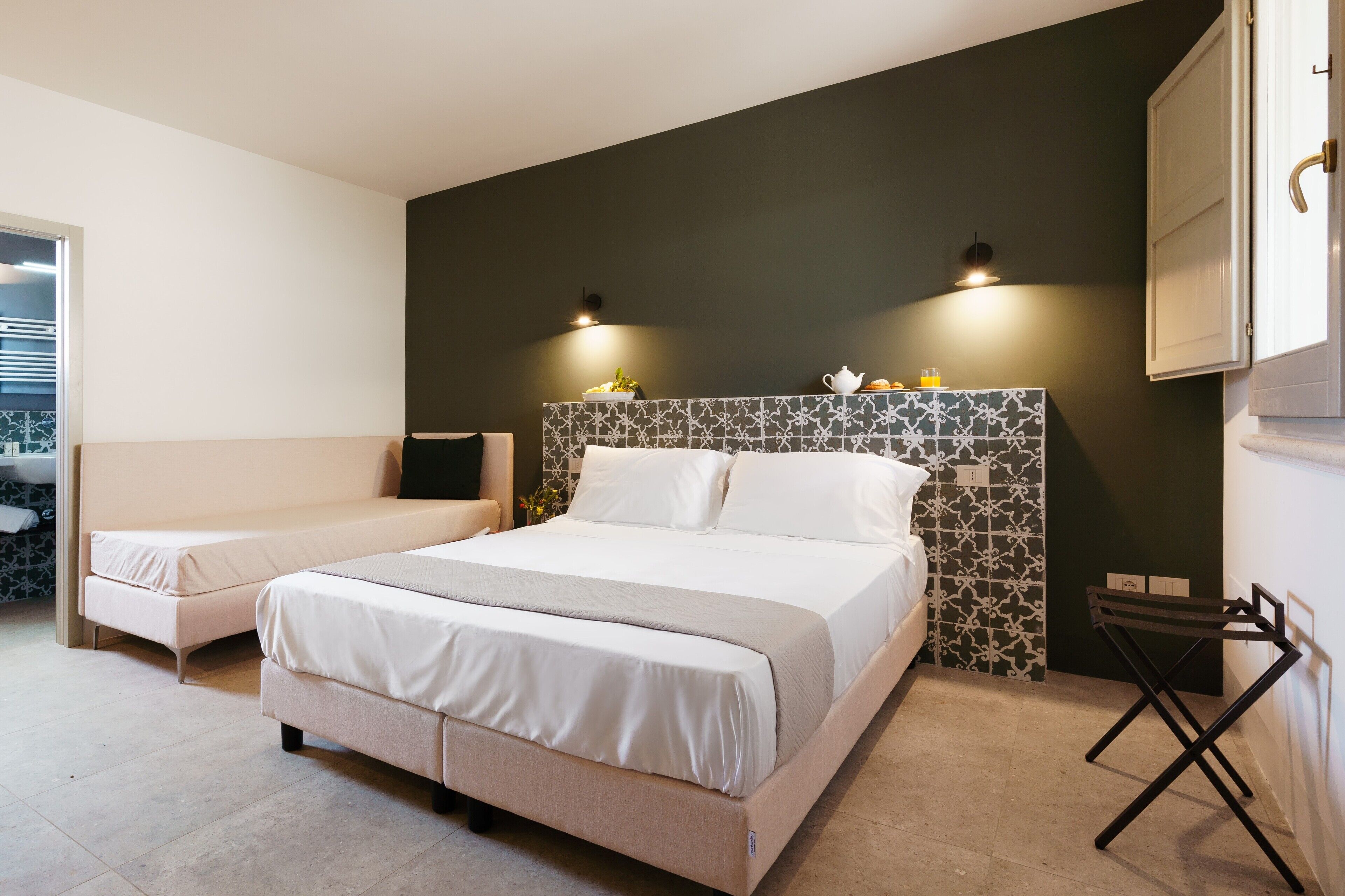 Un dormitorio moderno con una cama grande, una mesita de noche y una pequeña zona de estar.
