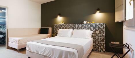 A modern bedroom with a large bed, a bedside table, and a small seating area.
