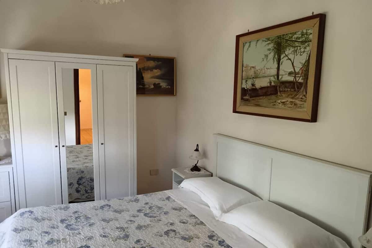 Une chambre à coucher avec un lit, une table de chevet, une armoire et un tableau au mur.