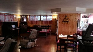Una sala de estar acogedora con un piano, una mesa de comedor y un banco.