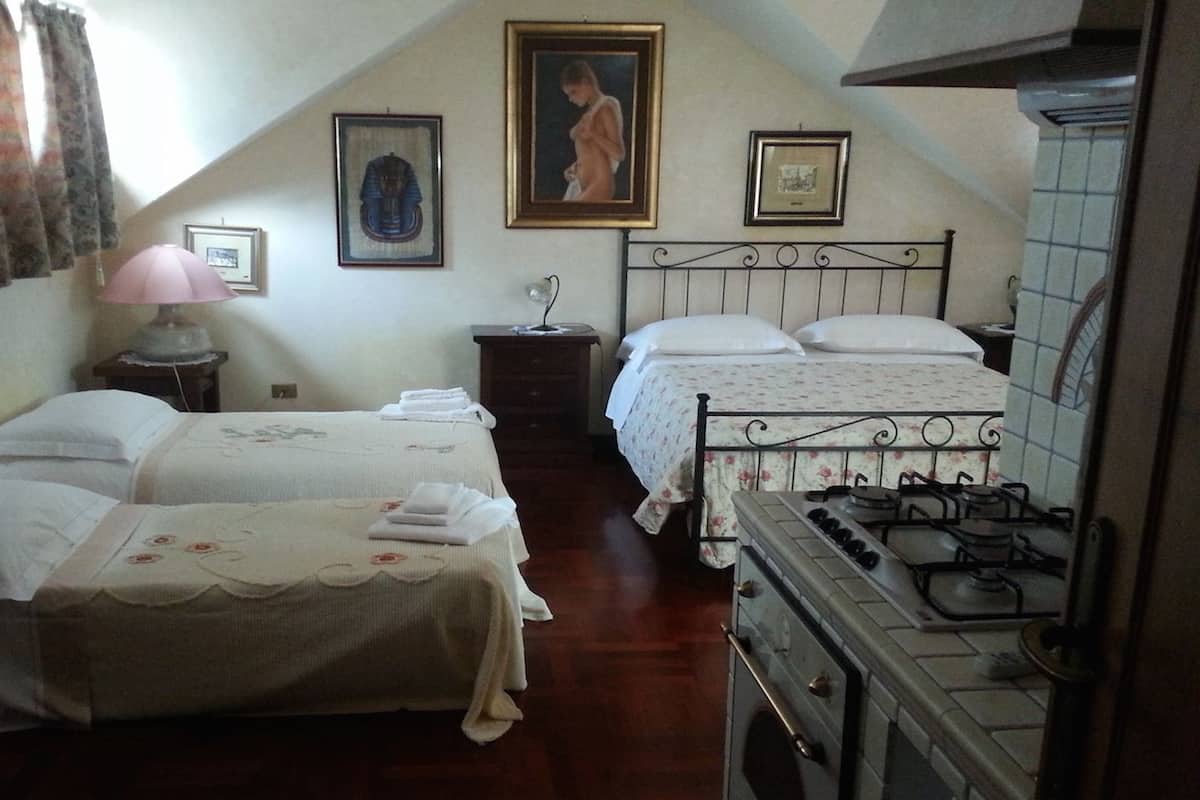 Une chambre avec deux lits, une table de chevet, une lampe et un poêle.
