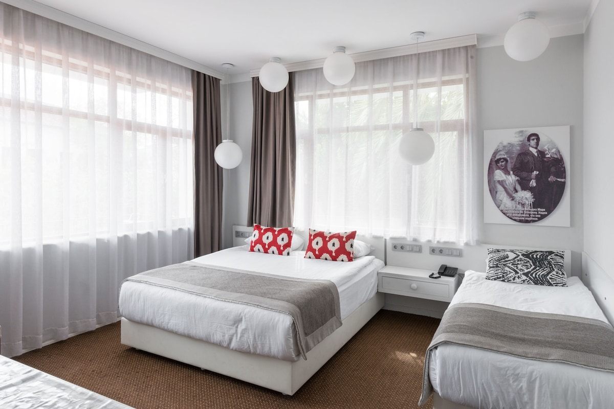 Habitació d'hotel moderna amb un llit gran, dues taules de nit i un escriptori petit.