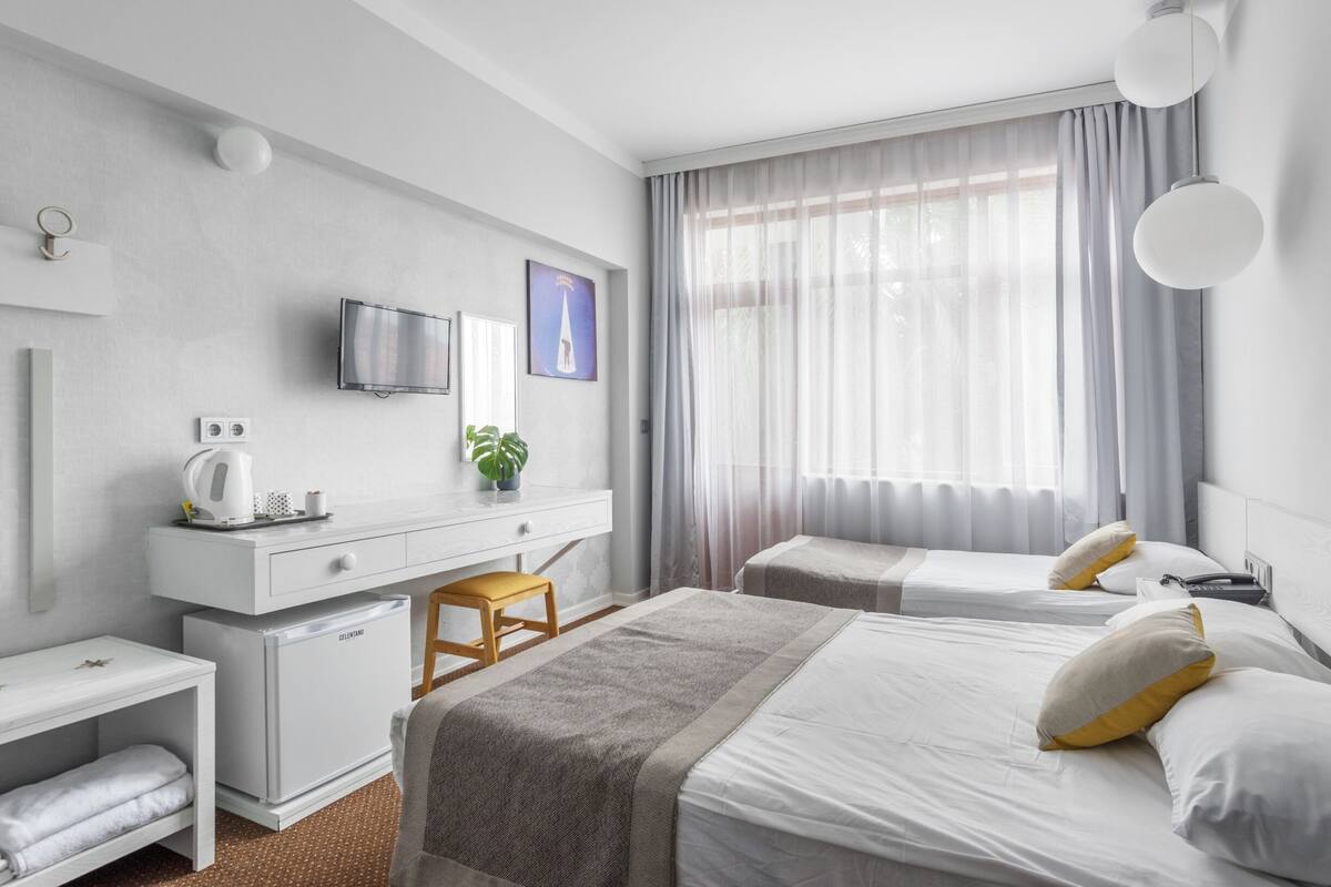 Ein modernes Hotelzimmer mit Bett, Nachttisch, Schreibtisch und Fernseher.