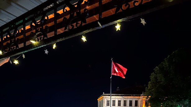 Ein Balkon mit Blick auf ein Gebäude, das eine Flagge, Lichterketten und Kerzen zeigt.