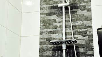 A shower with a rain showerhead and handheld showerhead, mounted on a stone wall.
