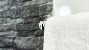 A bathroom with a stone wall and a white towel hanging on a rack. - Hotelli Havu (Uusikaupunki)