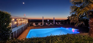 A rooftop pool area with lounge chairs and string lights. - Chambres d'hôtes Le Repère des Anges (Larnod)