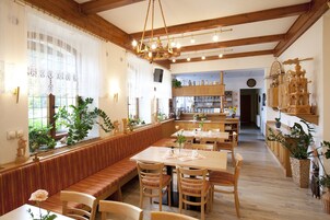Um restaurante com bancos e mesas de madeira, um candelabro e plantas em vasos.