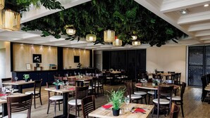 A restaurant with wooden tables and chairs, hanging plants, and pendant lights. - Hotel Mont Vernon (Saint-Marcel)