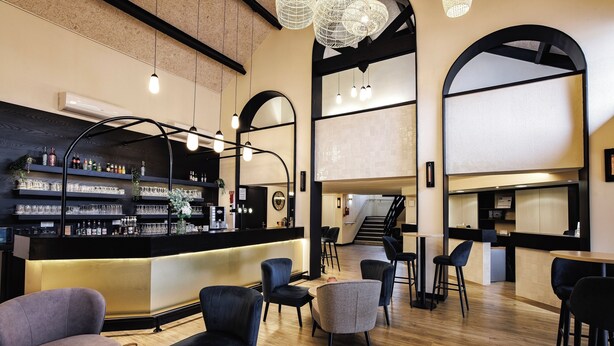 A modern bar area with a counter, seating, and a staircase. - Hotel Mont Vernon (Saint-Marcel)