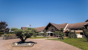 A building with a modern architectural style, featuring a mix of brick and stucco exteriors, and a central courtyard with a tree and a decorative stone planter. - Hotel Mont Vernon (Saint-Marcel)