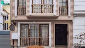 A multi-story building with a symmetrical facade, large windows with wooden railings, and a central entrance with steps. - Bucoleon Hostel (Istanbul)