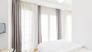 A hotel room with a bed, a TV, and large windows with curtains. - Bucoleon Hostel (Istanbul)