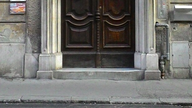 A double wooden door with an ornate archway, set in a stone building. - Golfo Della Luna (La Spezia)
