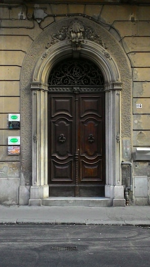 A double wooden door with an ornate archway, set in a stone building.