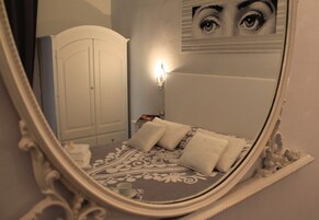 Un dormitorio con cama, armario y una lámpara fijada a la pared.