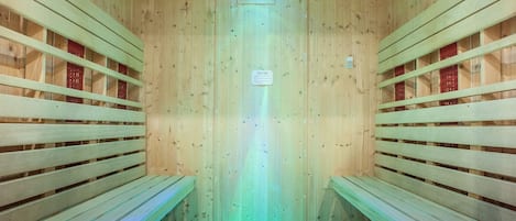 A sauna with wooden benches and a blue-lit floor.