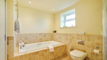 A bathroom with a bathtub, toilet, and a window providing natural light.