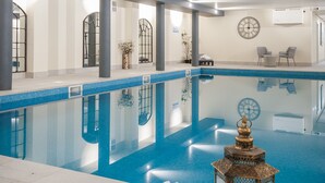 A modern indoor swimming pool with clear blue water, a white towel and slippers on the floor, and a decorative lantern. - COMIS Hotel & Golf Resort (Mount Murray)
