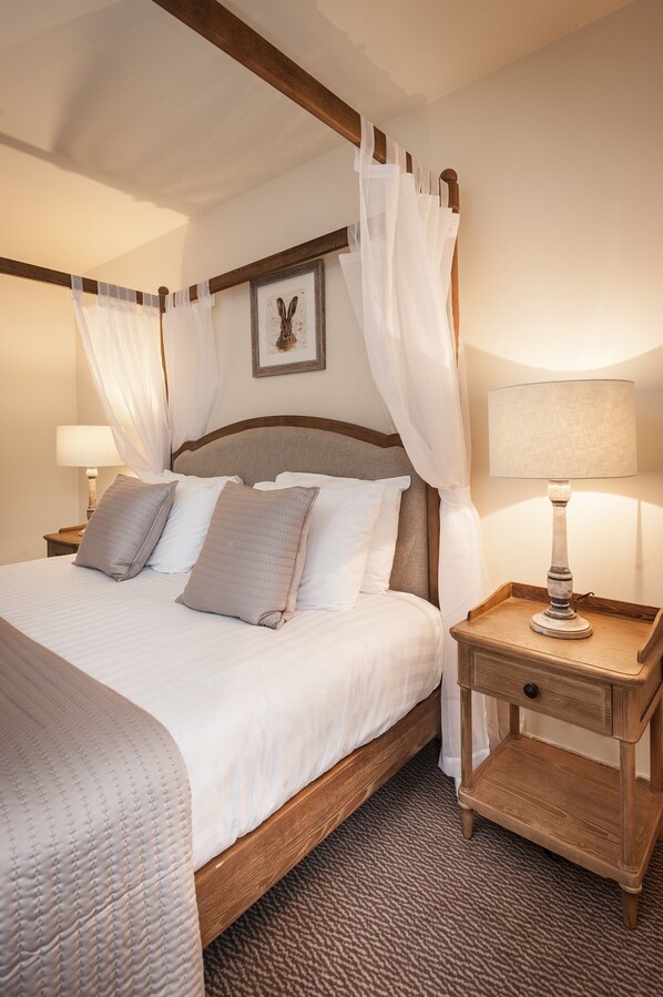 Un lit bien fait, avec une tête de lit en bois, une table de chevet avec une lampe et un cadre photo accroché au mur.