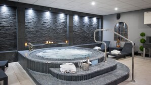 A spa area with a hot tub, seating, and a stone wall. - COMIS Hotel & Golf Resort (Mount Murray)