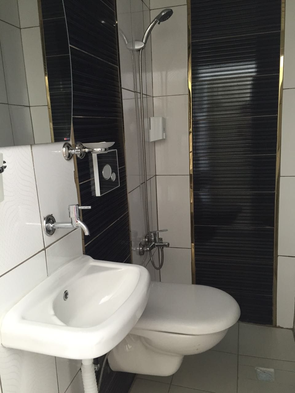 A modern bathroom with a white sink, toilet, and shower.