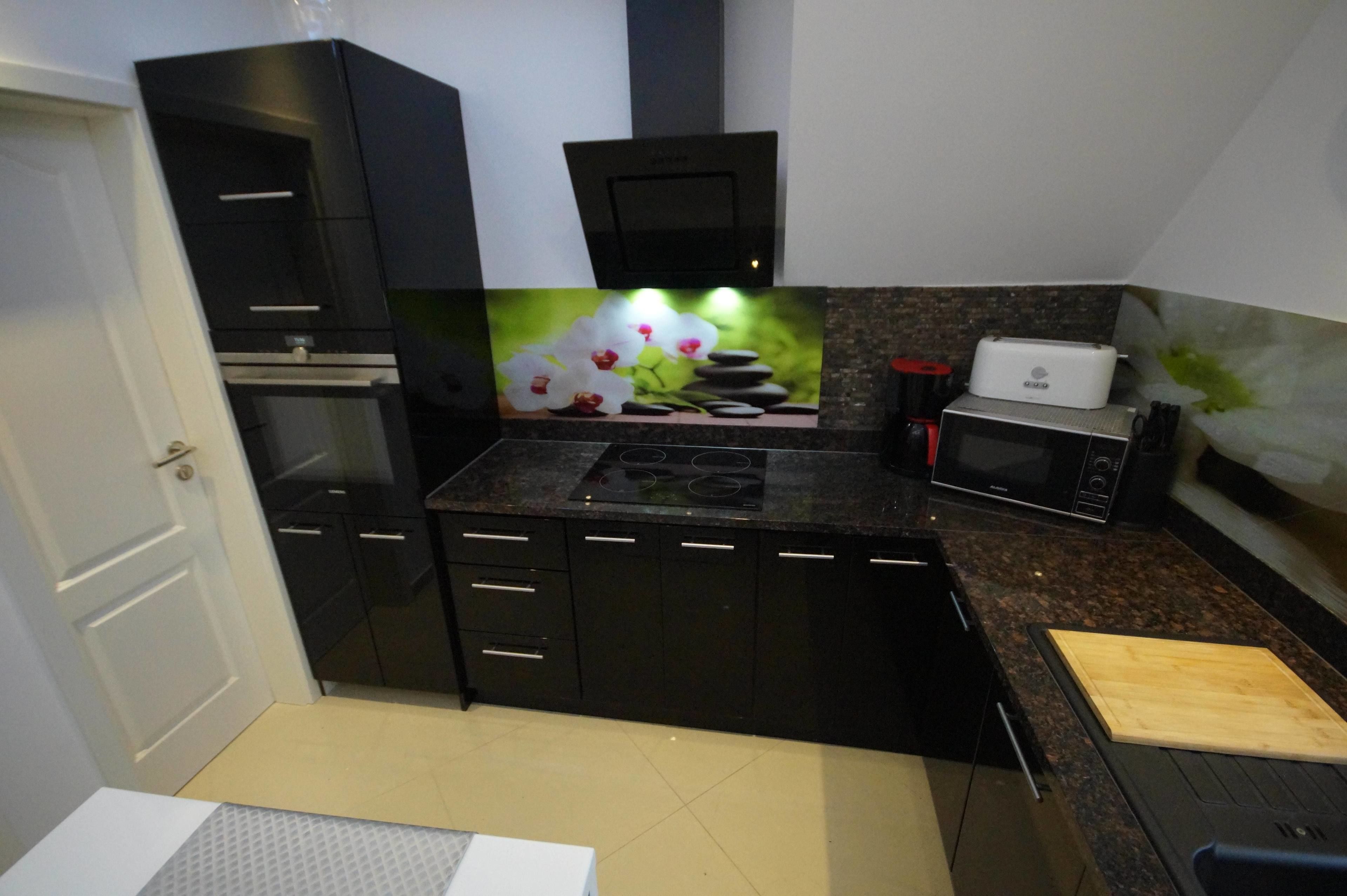 A compact kitchen with black cabinets, a microwave, a toaster, and a granite countertop.