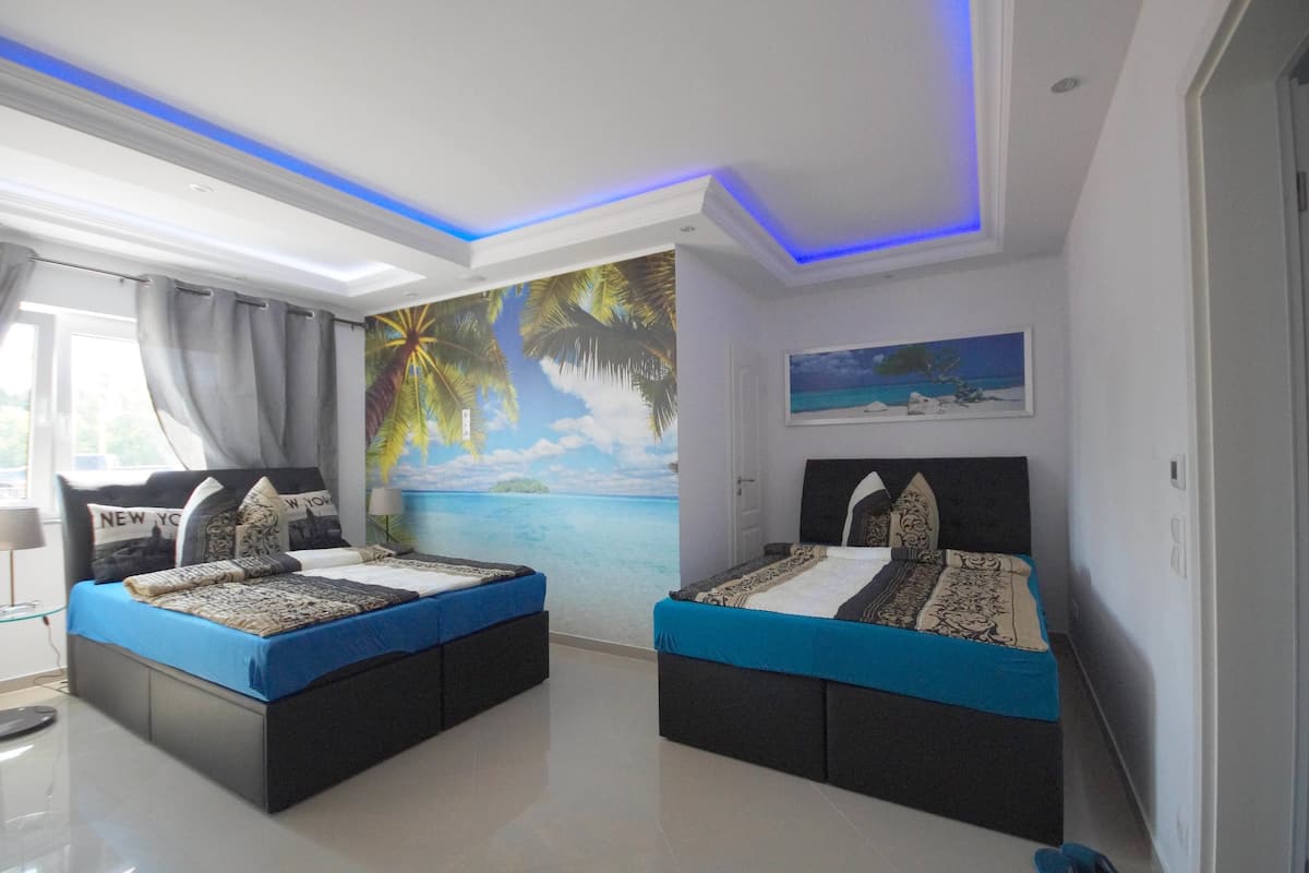 Quarto com duas camas, um mural com cena de praia e uma pintura de uma praia.