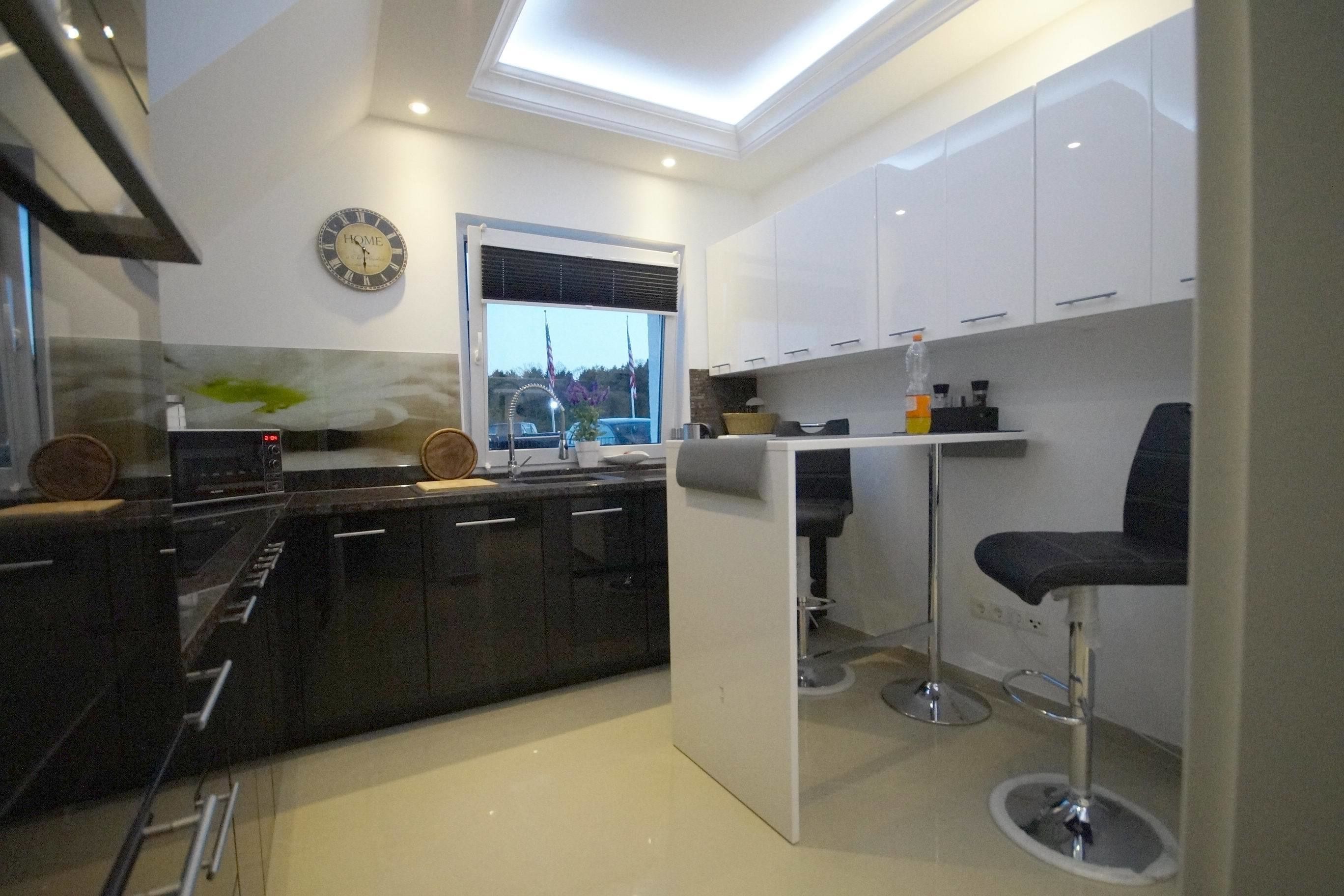 A modern kitchen with a skylight, a clock, and a bar area with stools.