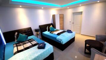 A modern hotel room with two beds, a small table, and a chair.