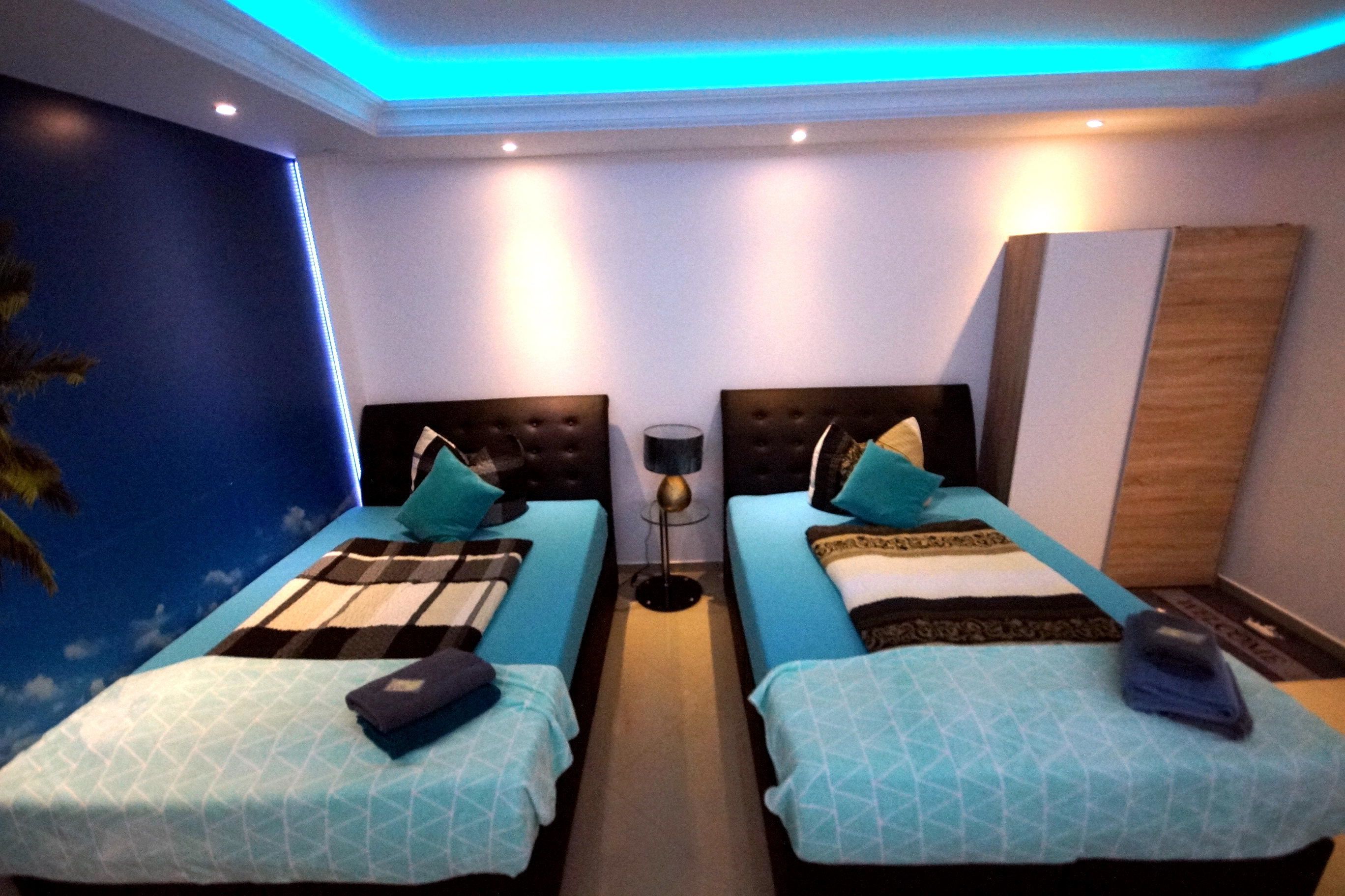 A hotel room with two beds, a nightstand, a lamp, and a wall mural.