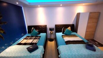 A hotel room with two beds, a nightstand, a lamp, and a wall mural.
