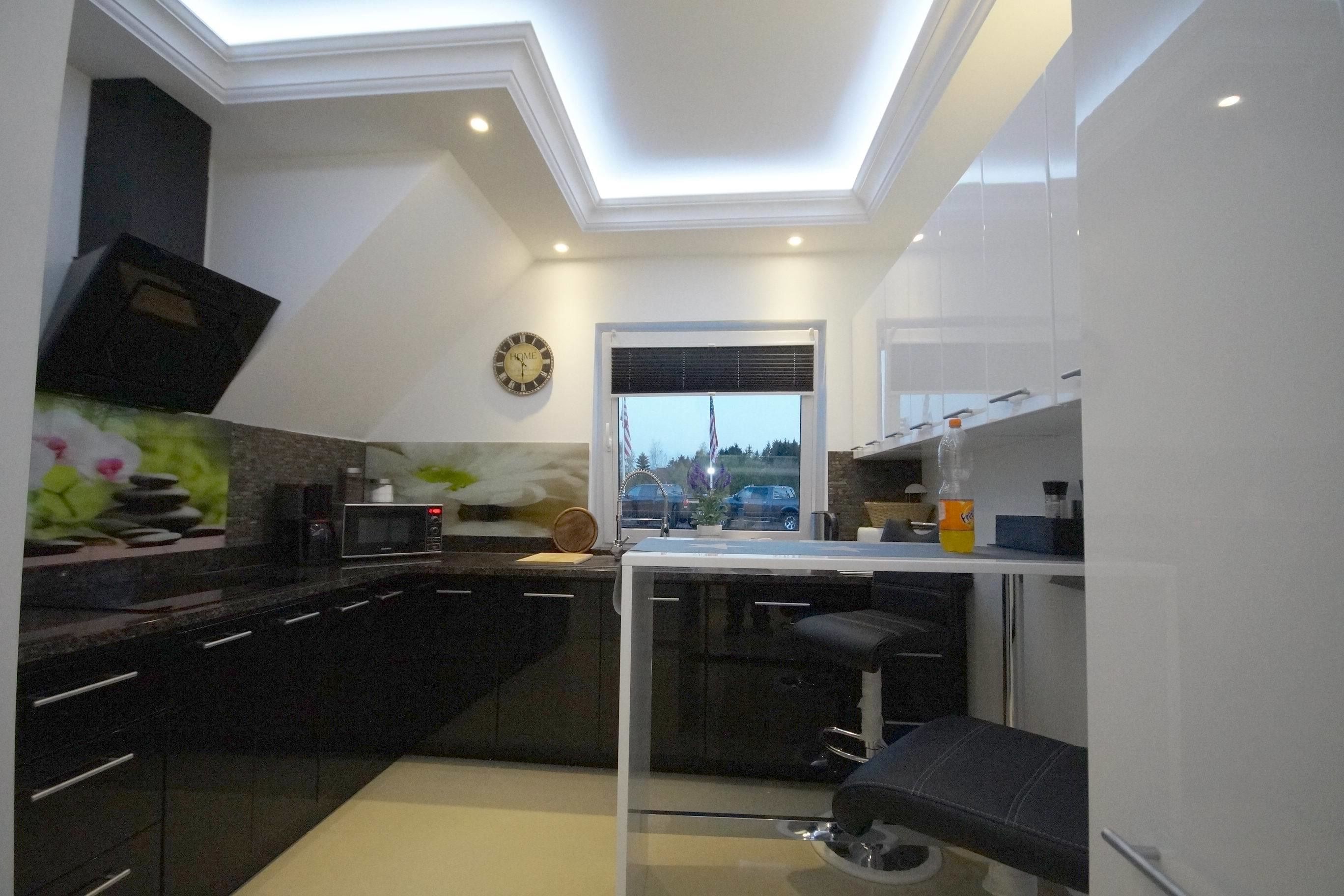 Una cocina moderna con armarios oscuros, una isla central, un microondas y un reloj en la pared.