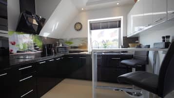 A modern kitchen with black cabinets, a microwave, and a coffee maker.
