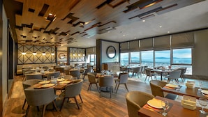 A spacious restaurant with high ceilings, wooden beams, and large windows offering a view of the sea. - Elite World Grand Istanbul Kucukyali  (Istanbul)