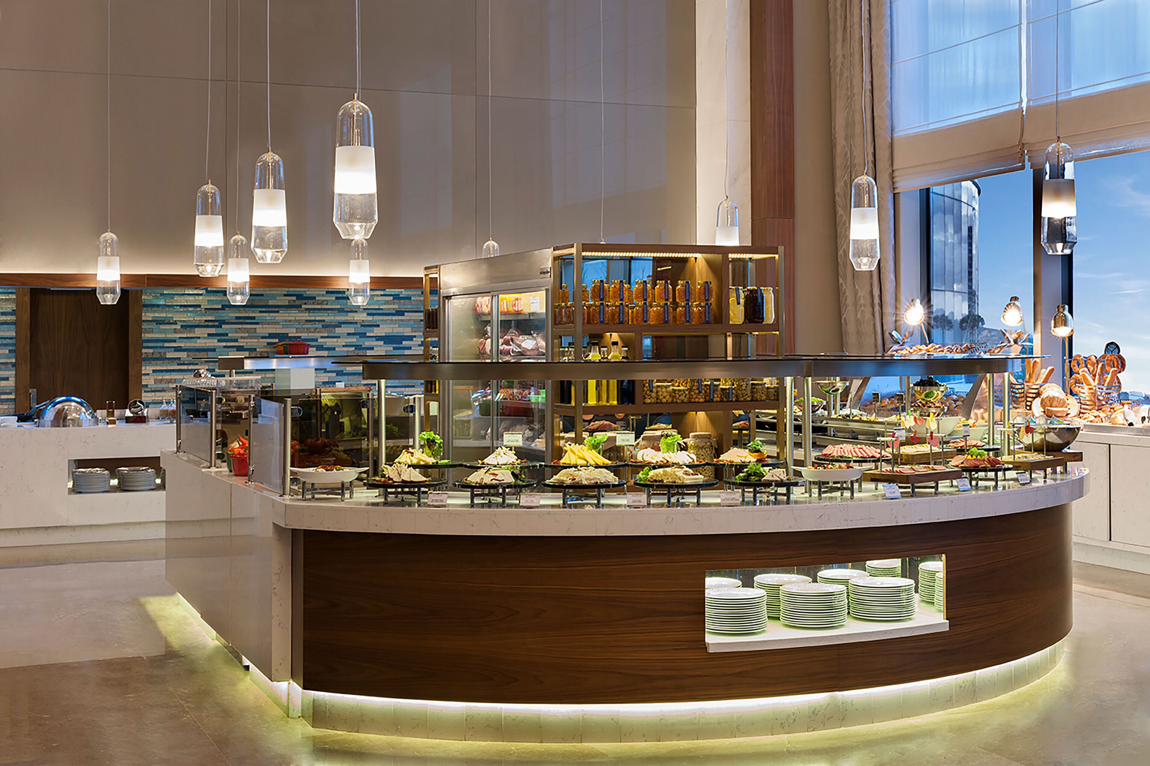 A buffet counter with various food items and a glass display case, surrounded by hanging pendant lights.