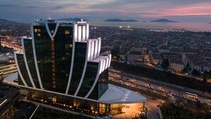 A modern building with a unique curved design, located near a busy road and a body of water. - Elite World Grand Istanbul Kucukyali  (Istanbul)