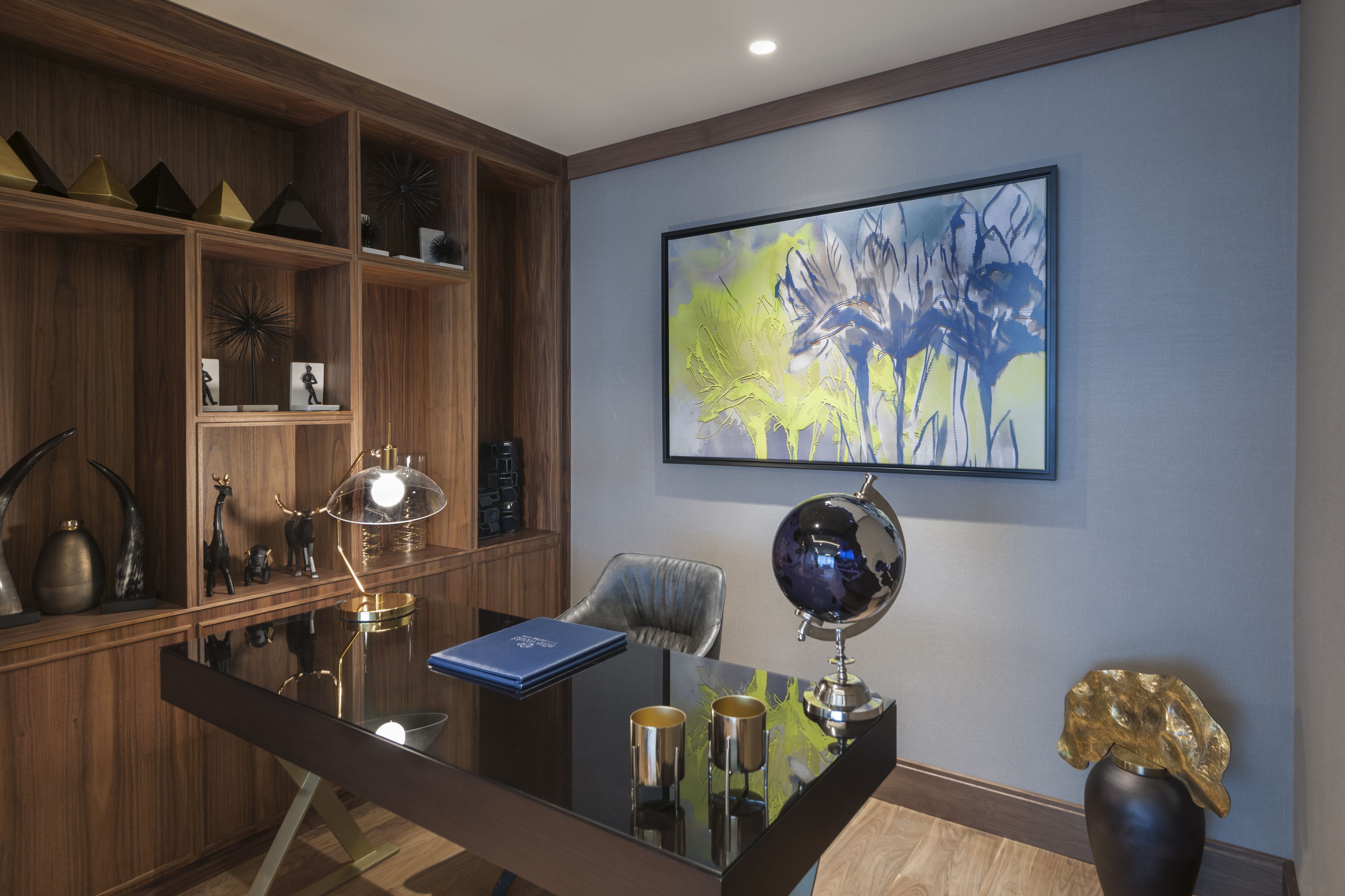 A modern office with a wooden desk, a globe, and a blue book.