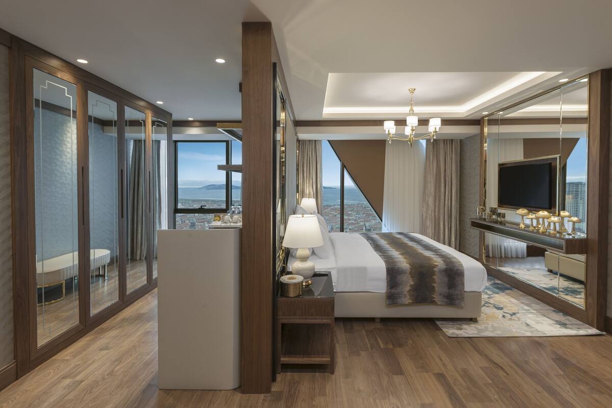 Et moderne hotelværelse med en stor seng, et skrivebord, et fjernsyn og udsigt over byen.