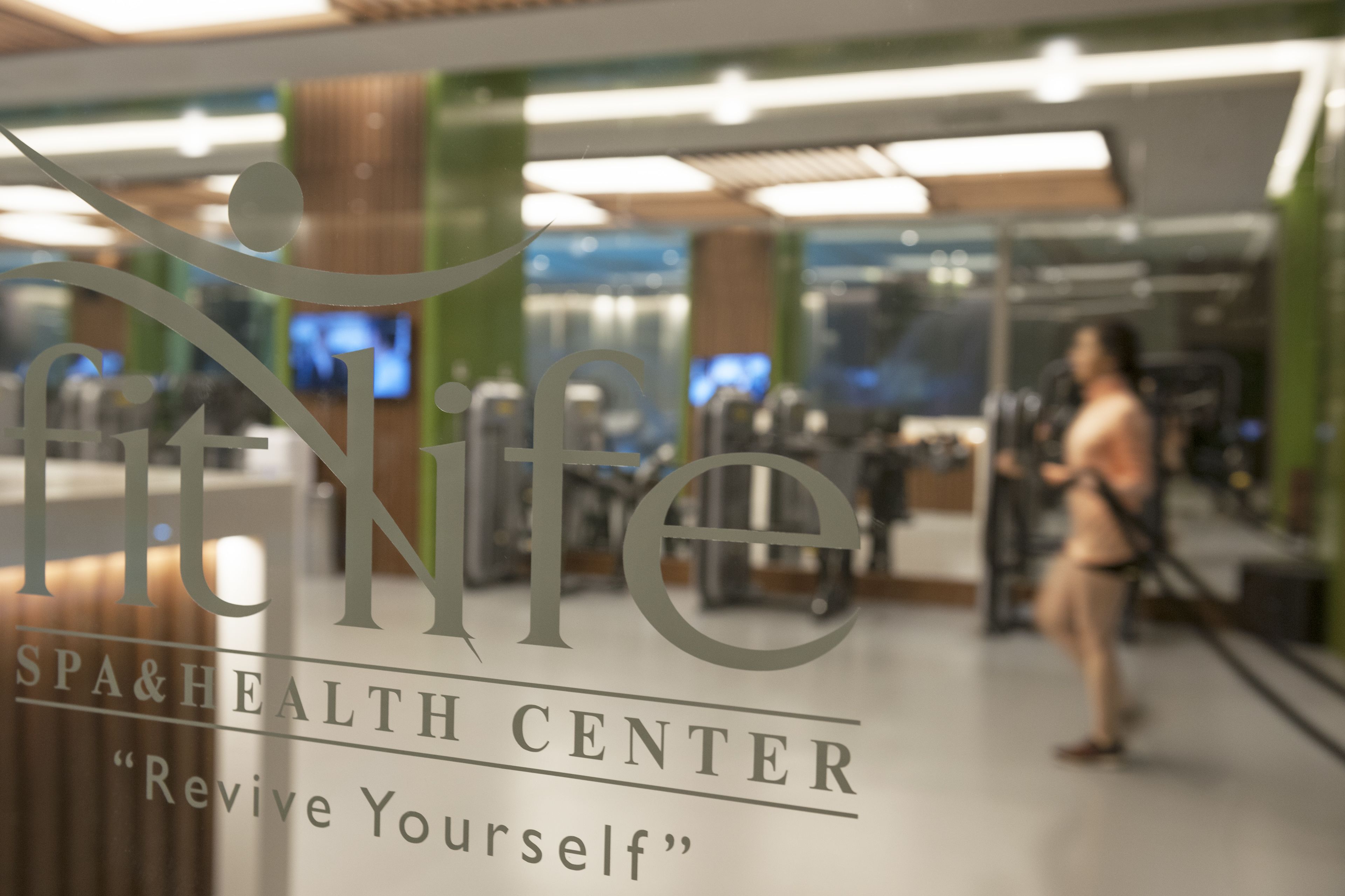 A gym interior with a large sign reading "Spa & Health Center" and the slogan "Revive Yourself".