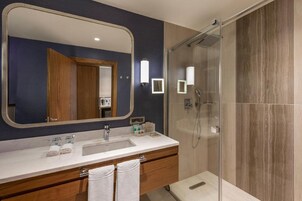 Un bagno moderno con uno specchio grande, due lavabi, una doccia e mobili in legno.