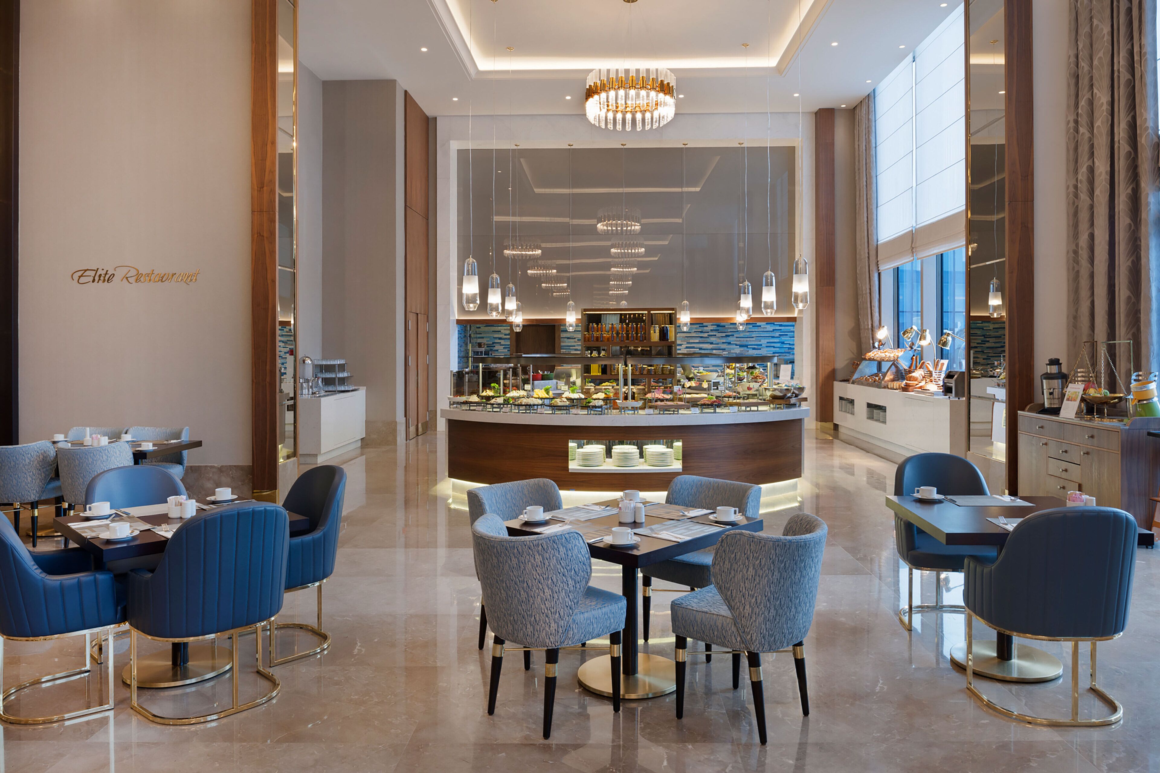 A modern restaurant with blue upholstered chairs and a central bar area.