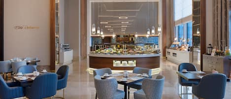 A modern restaurant with blue upholstered chairs and a central bar area.