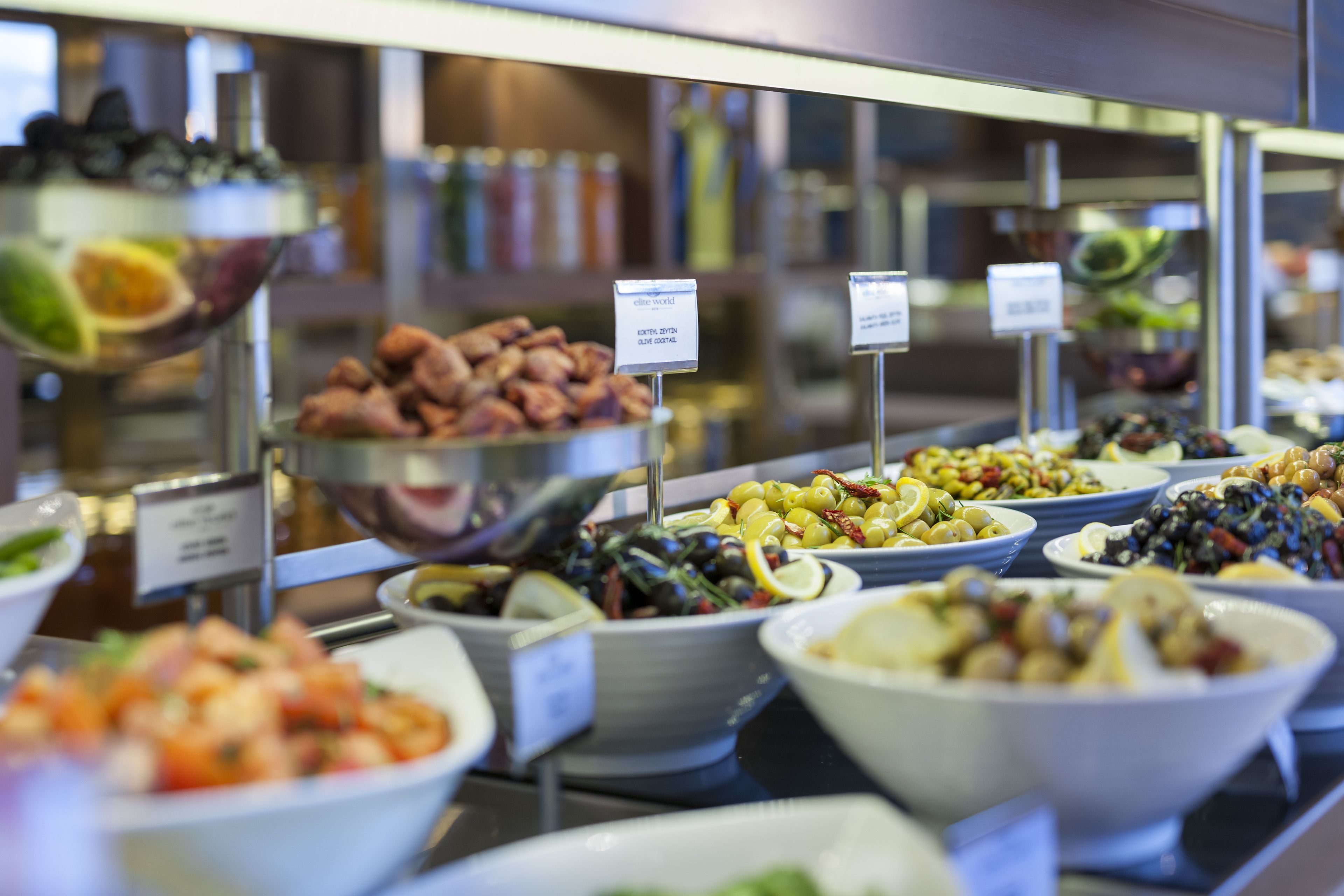 Un buffet proposant une variété de plats, notamment des salades, des olives et d’autres aliments préparés.