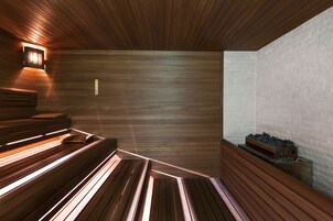 Eine Sauna mit Holzbänken und einer Steinwand.