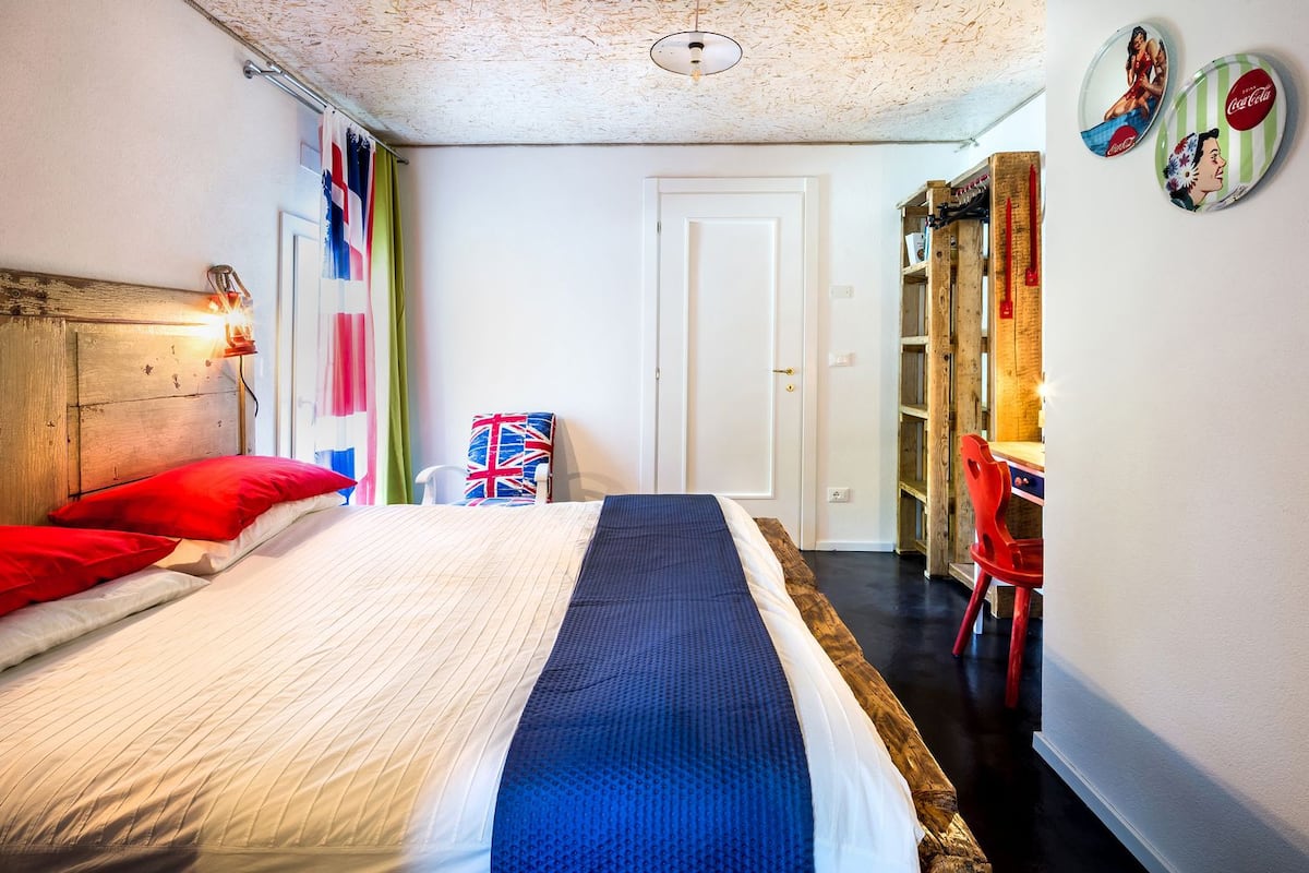 A bedroom with a bed, a chair, a wardrobe, and a door.