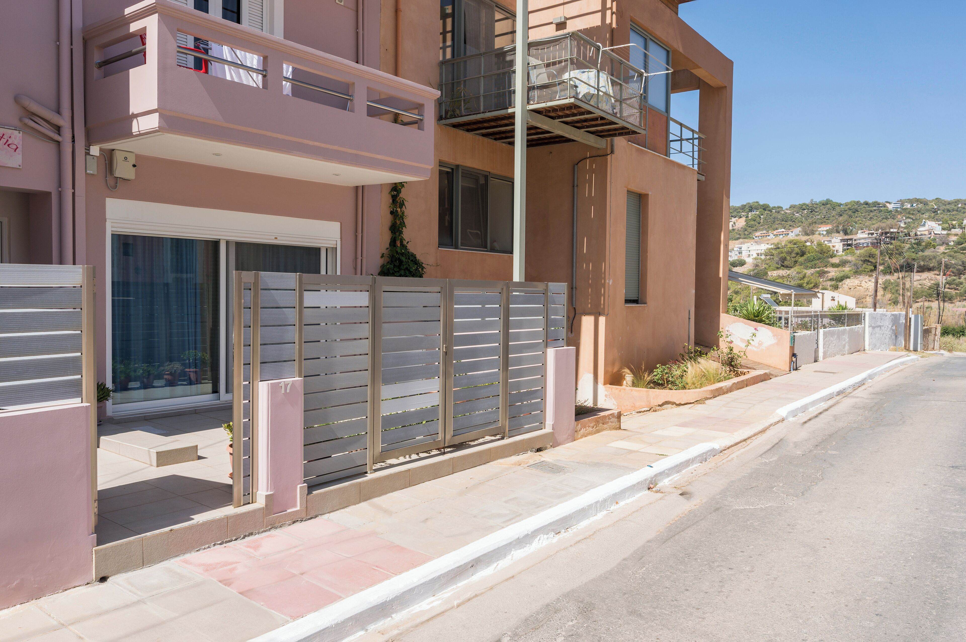 Un edificio moderno de dos pisos con un balcón, una entrada con portón y vistas a un paisaje montañoso.