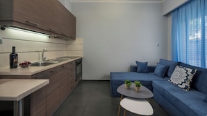 Une cuisine moderne avec des meubles en bois, un évier et un plan de travail. On y trouve un canapé bleu avec des coussins et une petite table avec des plantes.