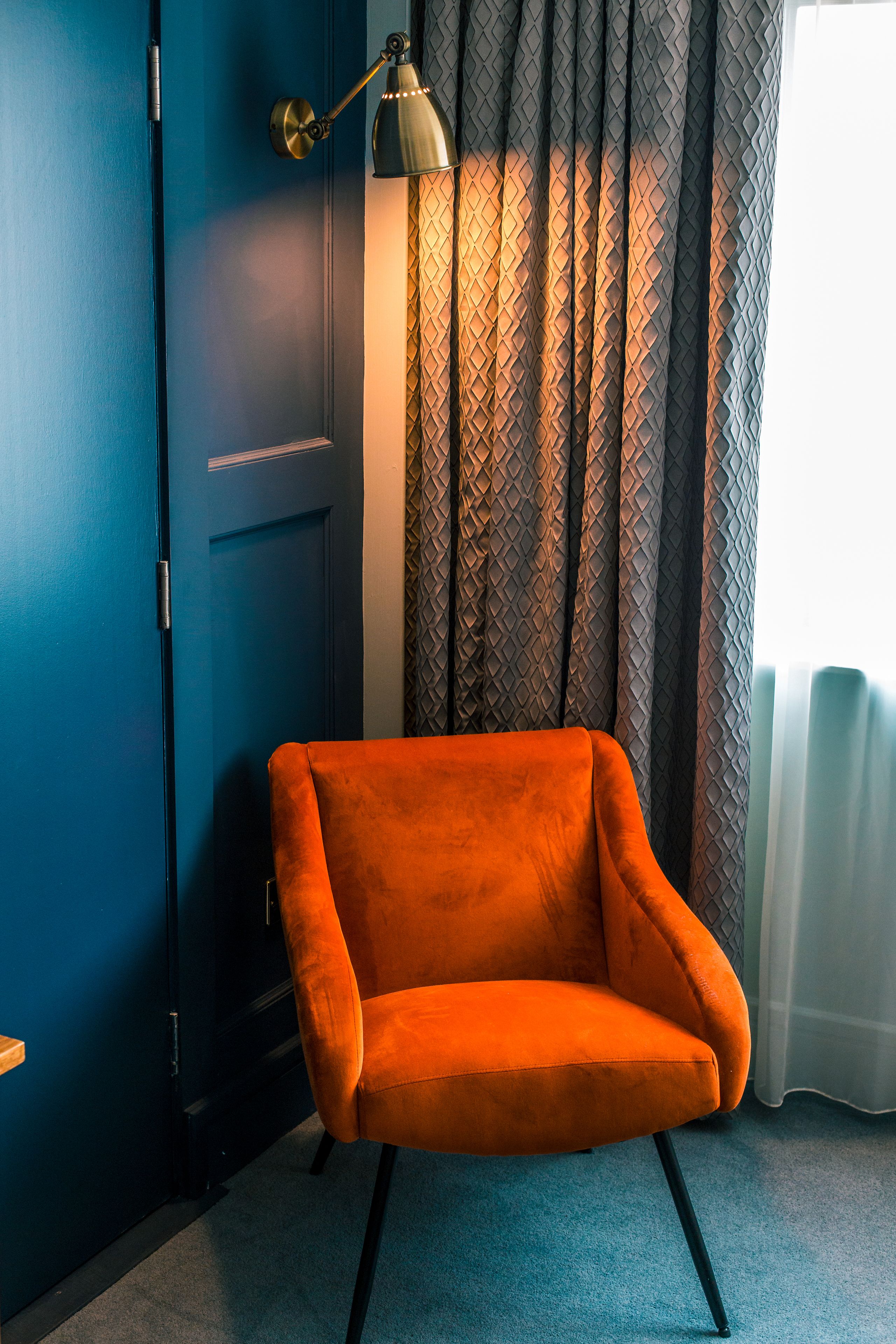 A room with a blue door, a modern lamp, and a patterned curtain.