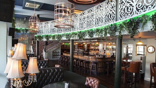 Uma área de bar com assentos de couro, balcão e iluminação decorativa.